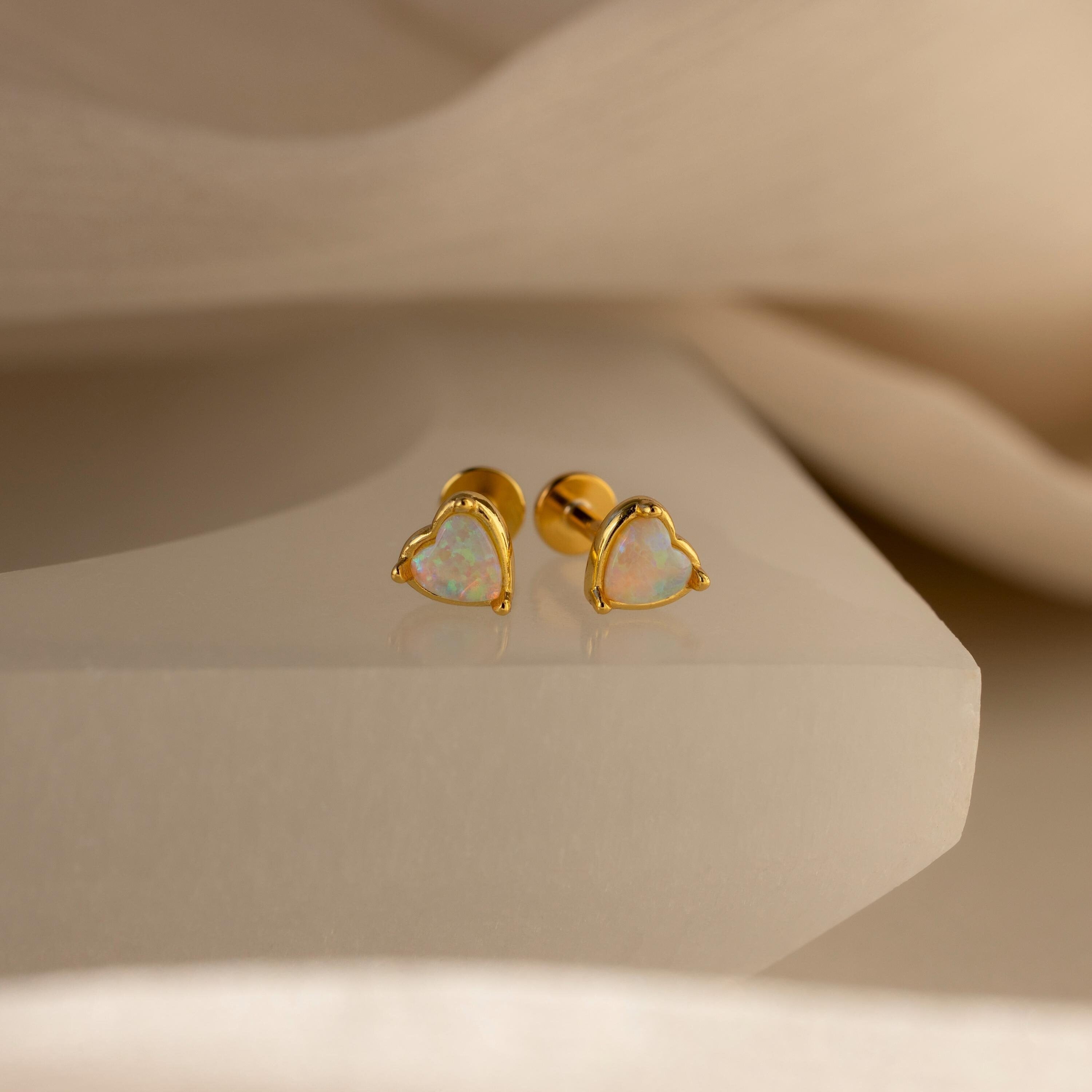 A pair of heart-shaped opal flat back stud earrings set in 925 sterling silver, displayed against a neutral background.